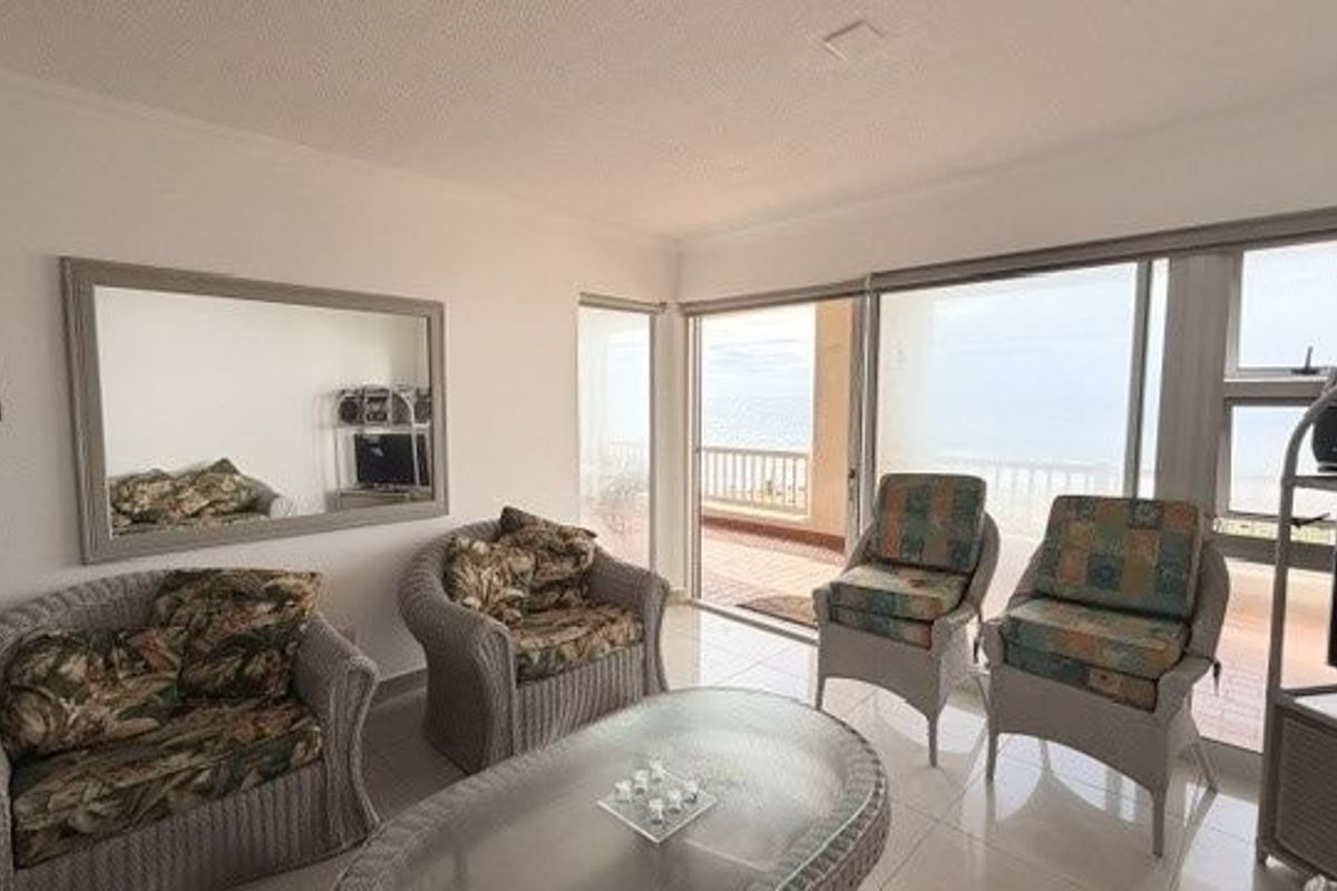 A bright living room featuring tiled flooring and large sliding glass doors that provide direct access to an outdoor balcony area.