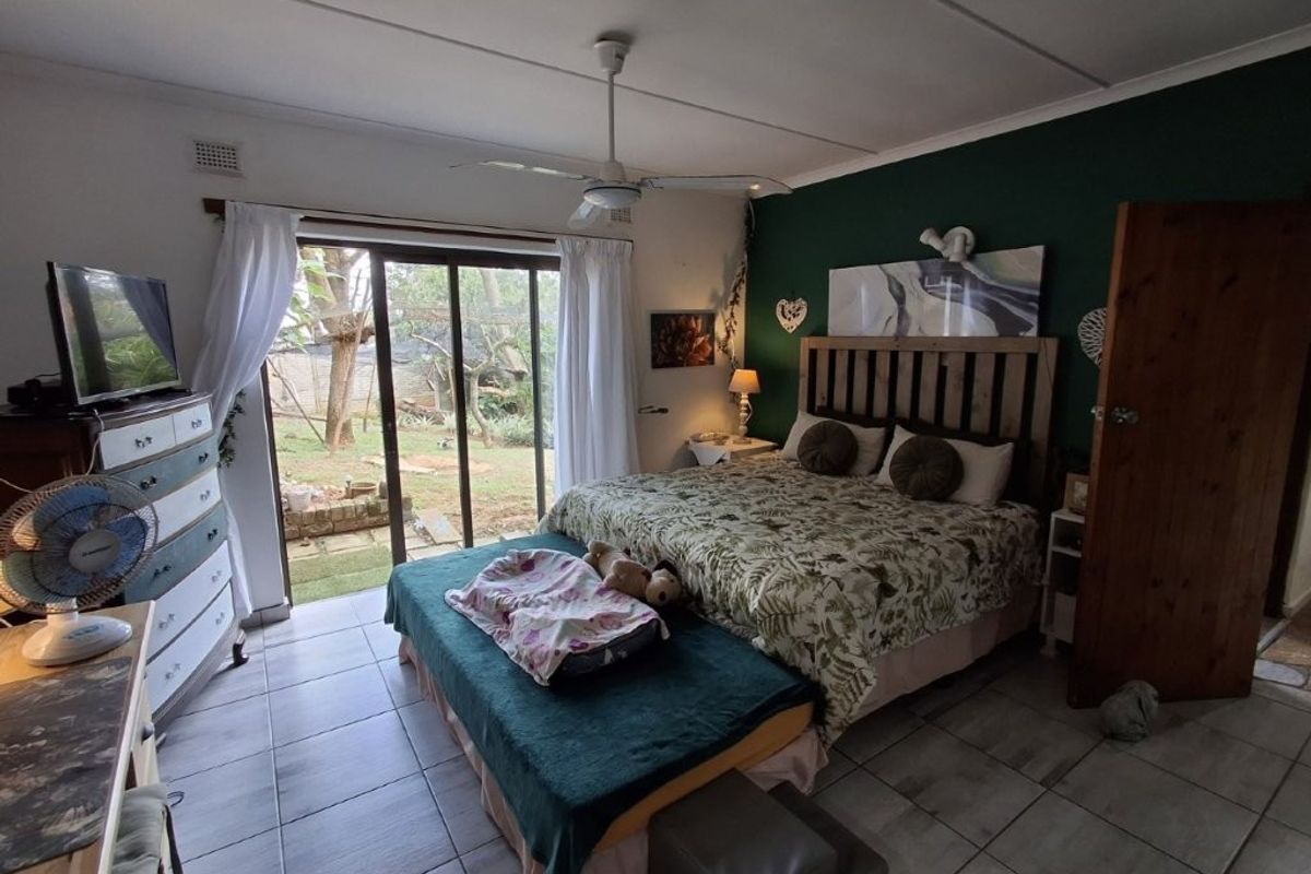 Spacious bedroom featuring tiled flooring, a ceiling fan, and large sliding glass doors providing direct access to the garden area.