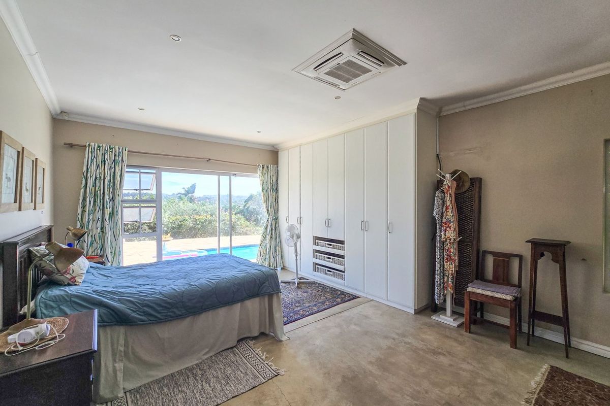 Spacious bedroom featuring polished concrete floors, extensive built-in cabinetry, and large sliding glass doors providing direct access to the pool area.