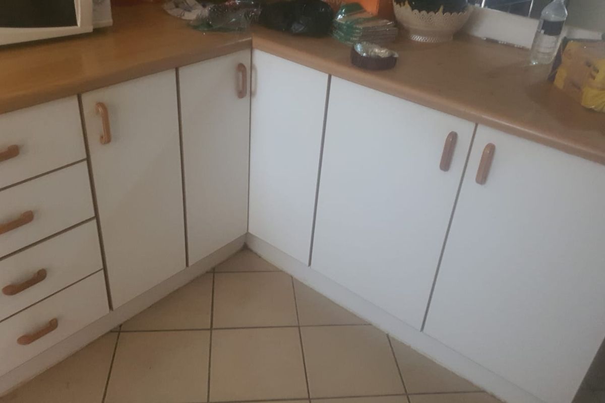 A functional kitchen corner featuring white cabinetry, laminate countertops, and ceramic floor tiles, offering a clean and practical workspace.