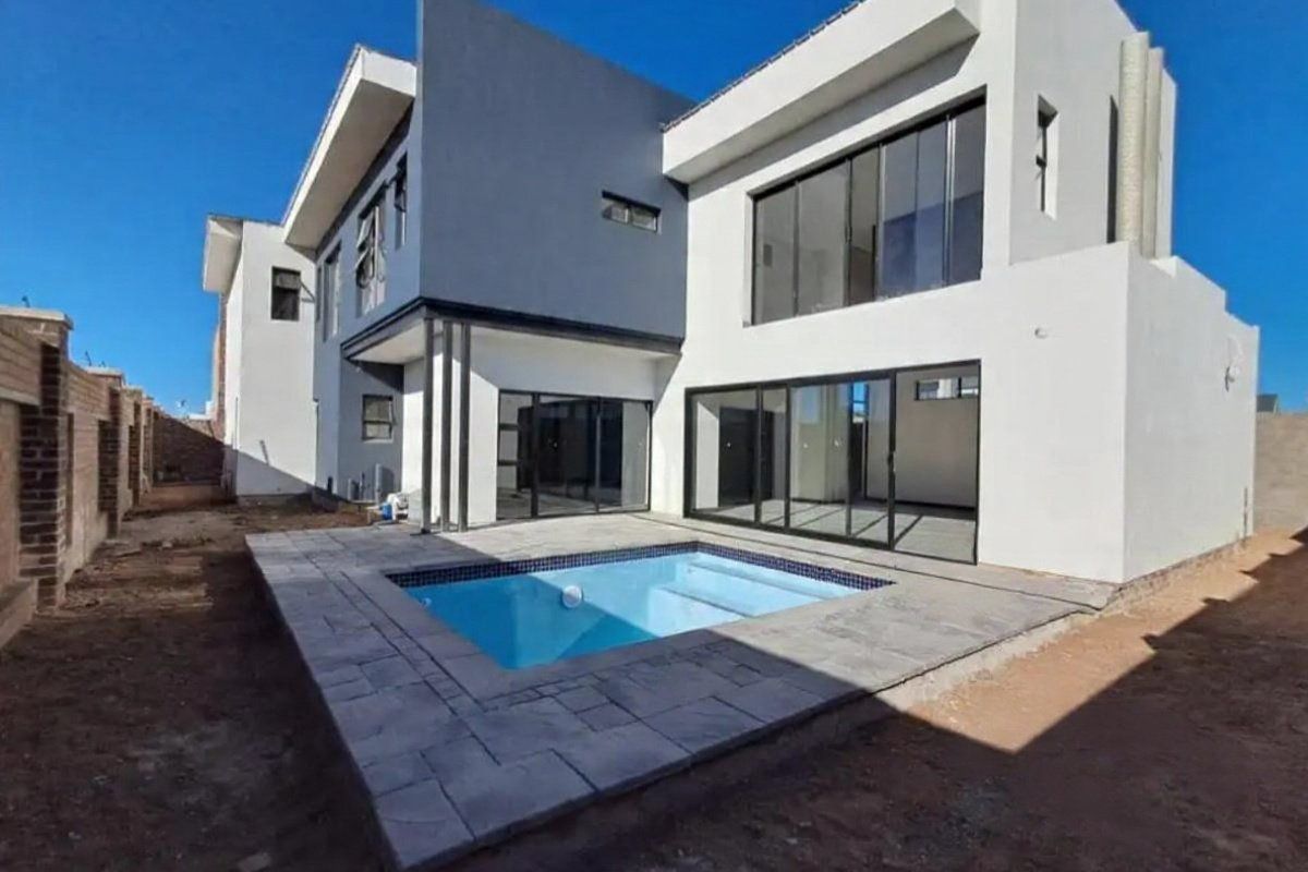 Modern double-story residence featuring a rear patio, swimming pool, and large sliding glass doors, set within a contemporary architectural design.