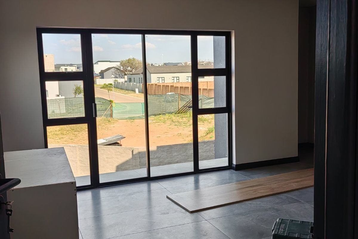 A bright, modern living area featuring large aluminium sliding doors, neutral walls, and contemporary tiled flooring, offering a clean canvas for interior design.