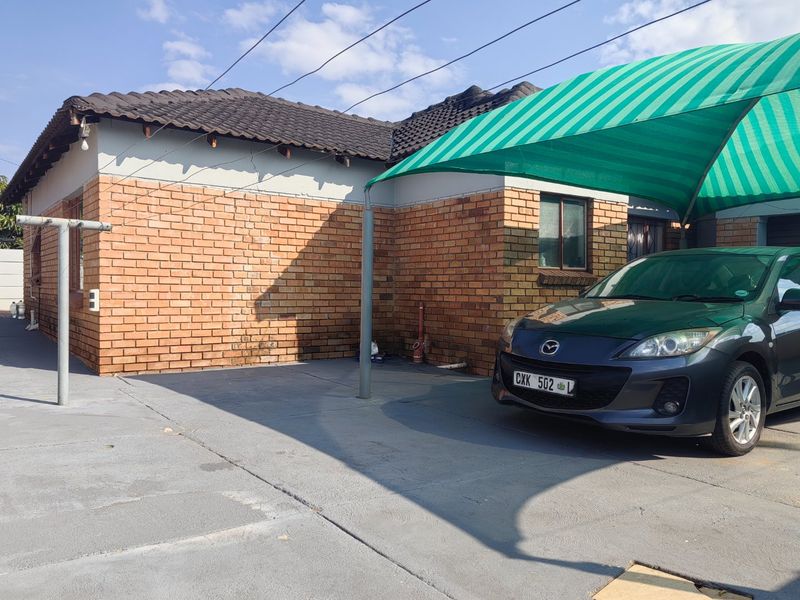 Front exterior view of the property featuring a face brick facade, tiled roof, and a concrete driveway with a shade cloth carport.