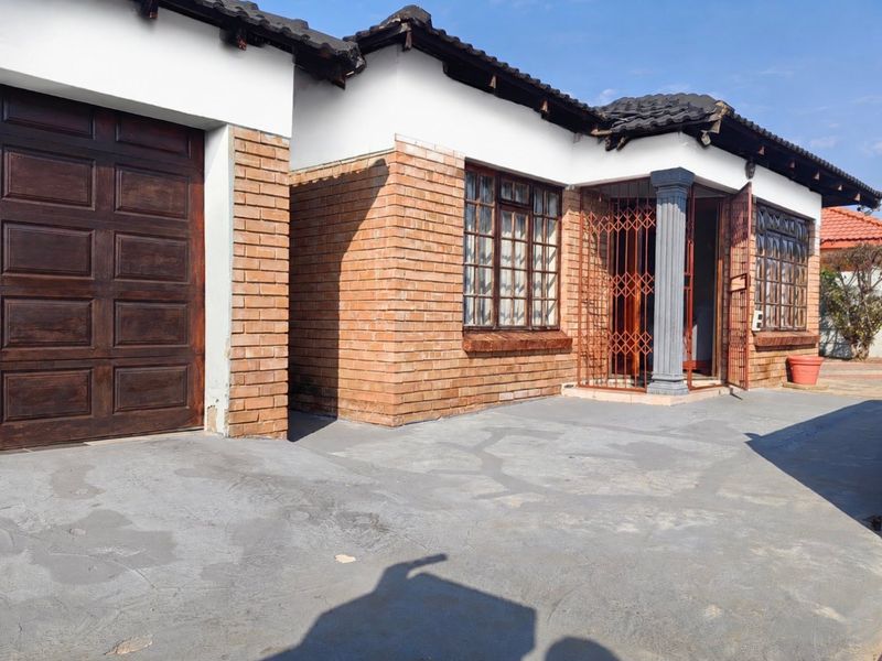 Front exterior view of a face brick house featuring a garage, concrete driveway, and security gate entrance.