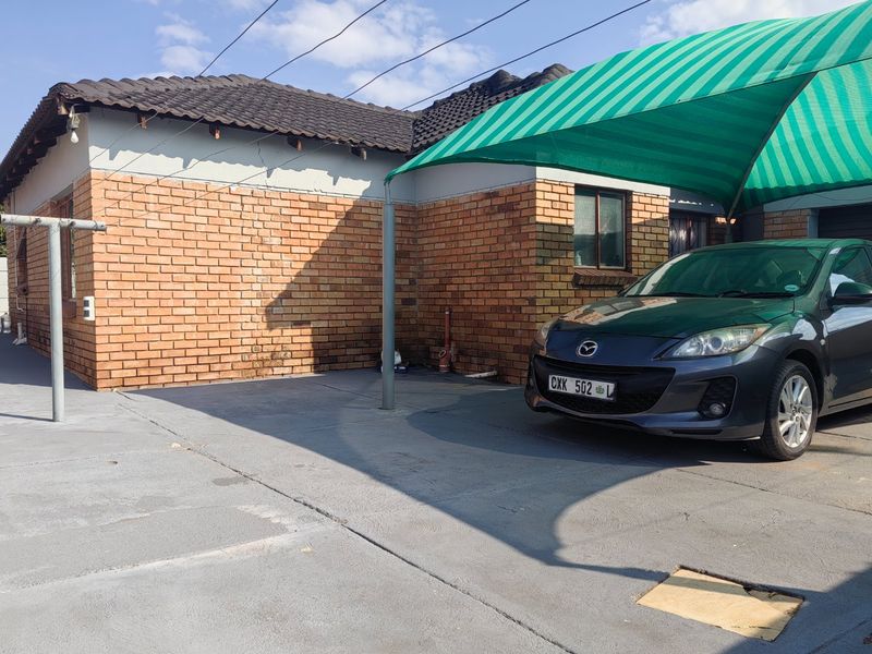 Exterior view of the property featuring a face brick facade, concrete driveway, and a green shade cloth carport structure.
