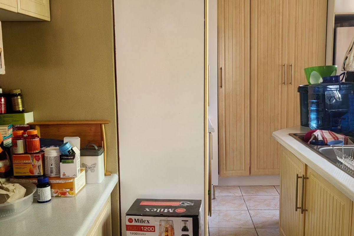 A dated kitchen area featuring light wood-toned cabinetry, laminate countertops, and tiled flooring, offering potential for a modern renovation.