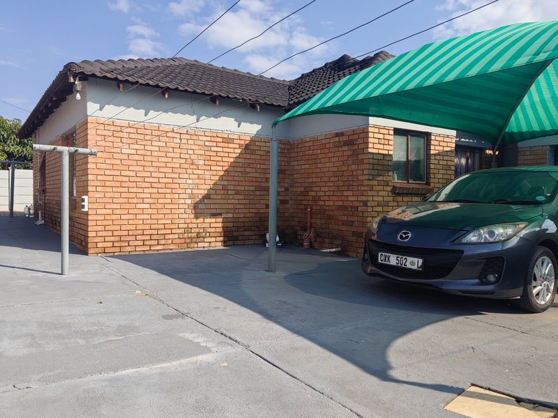 Front exterior view of the house featuring a face brick facade, concrete driveway, and a green shade cloth carport.