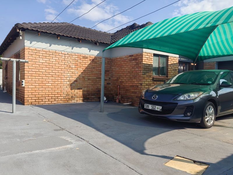 Front exterior view of the house featuring a face brick facade, concrete driveway, and a green shade cloth carport.