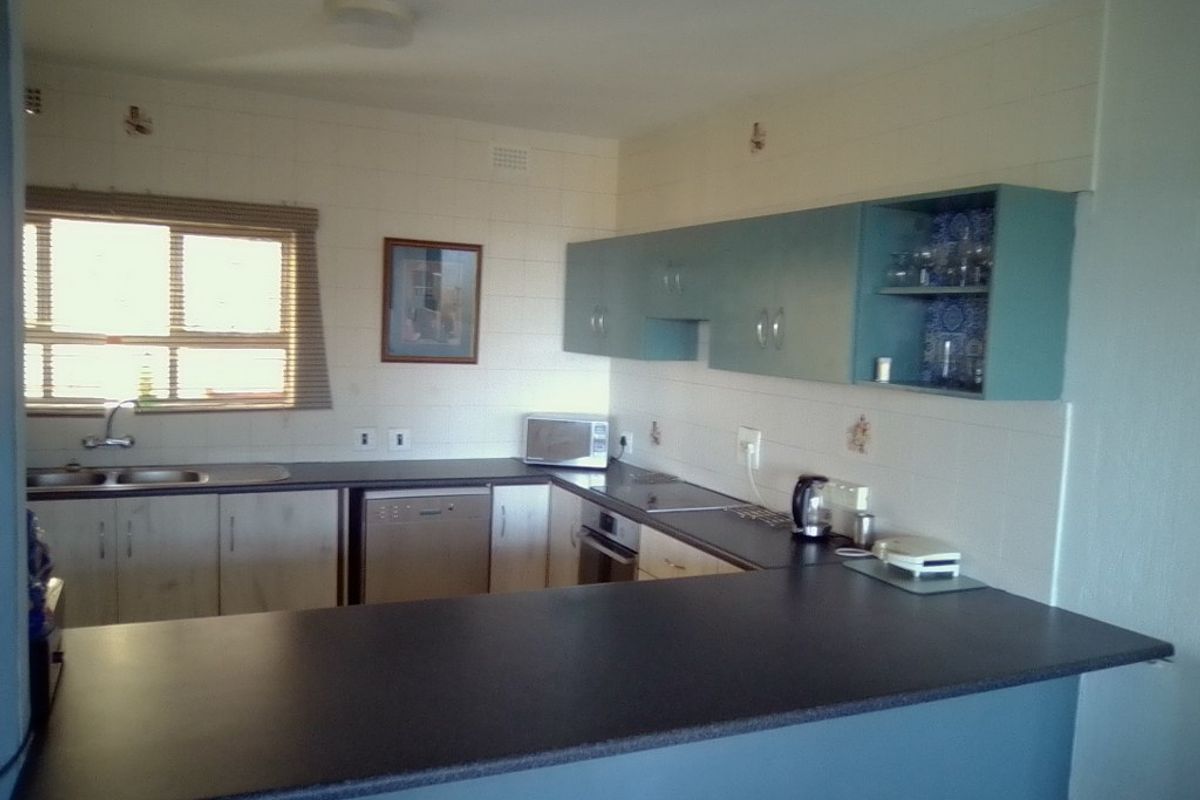 A functional kitchen featuring a breakfast bar, built-in oven, hob, and ample cabinetry, offering a practical layout for daily meal preparation.