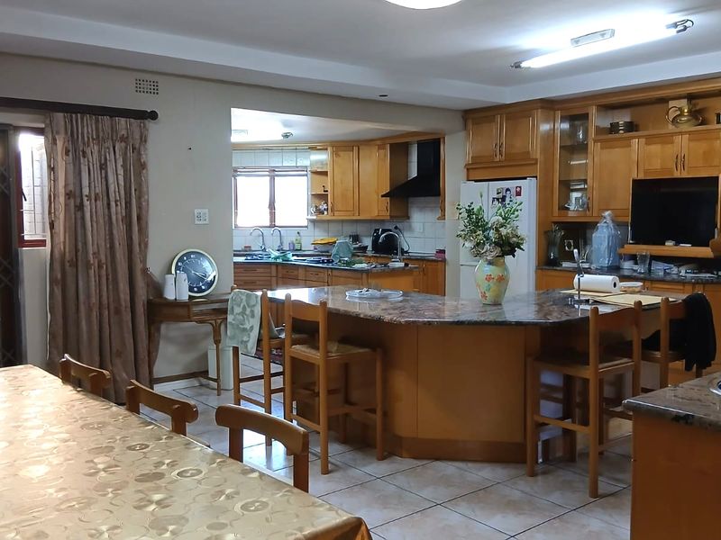 Spacious open-plan kitchen and dining area featuring wooden cabinetry, granite countertops, a central island, and direct access to the outdoor area.