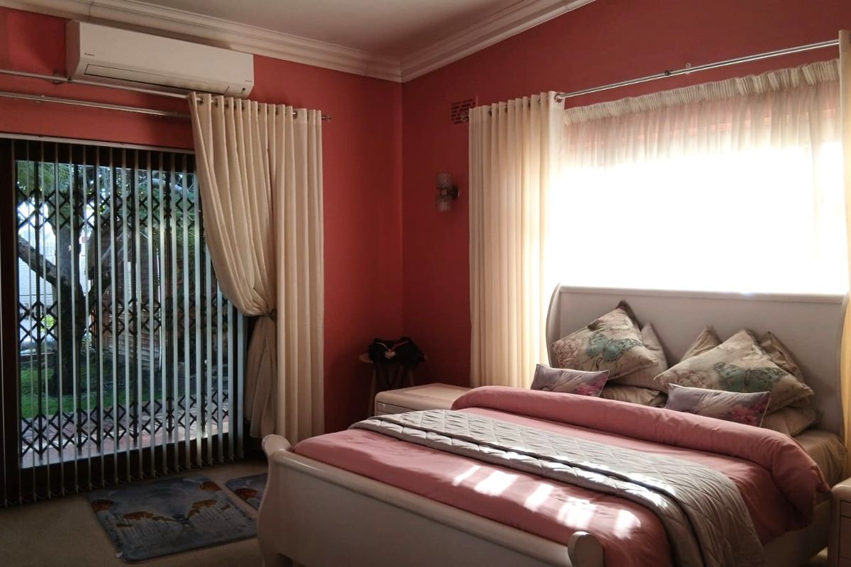 A bedroom featuring a split-system air conditioner, sliding glass door with security gate, and direct access to the garden area.