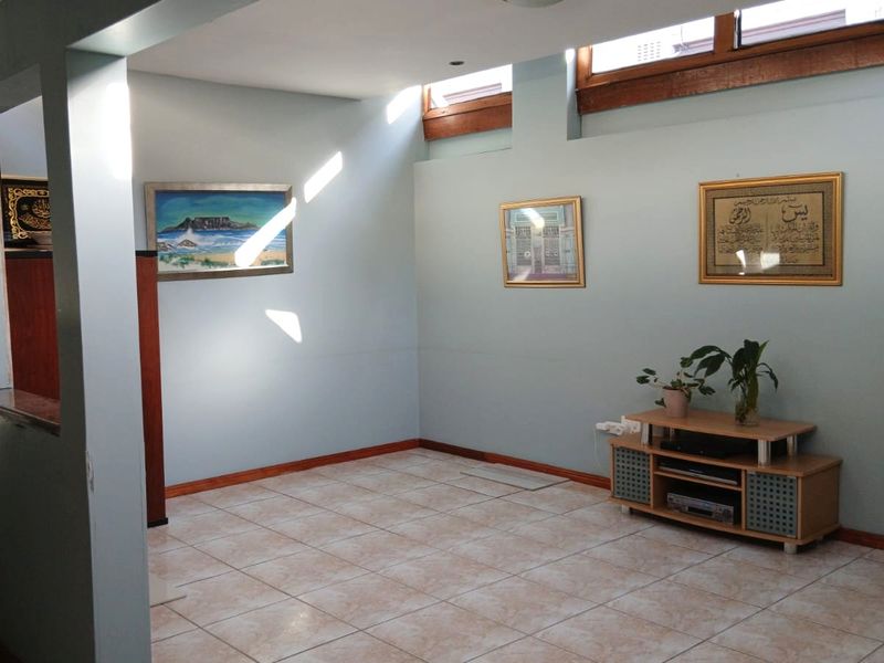 A living area featuring light-colored floor tiles, pale blue walls, and high-level clerestory windows that provide natural light.