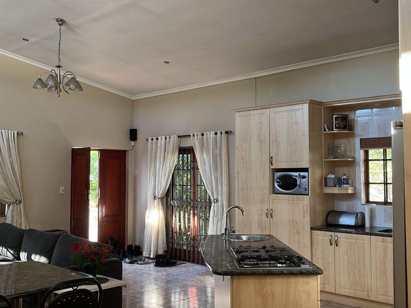 Open-plan living area featuring a kitchen with light wood cabinetry, gas hob, island, and direct access to the exterior through a security gate.