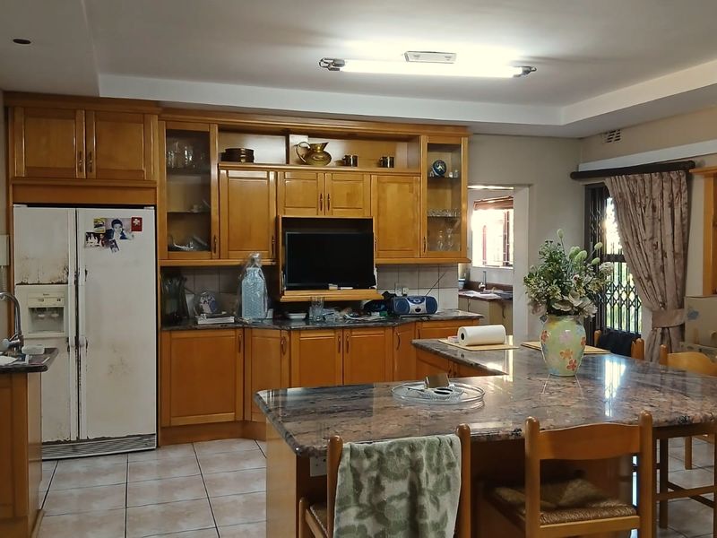 Spacious kitchen featuring extensive wooden cabinetry, granite countertops, a central island, and tiled flooring, offering a functional layout with potential for modern updates.