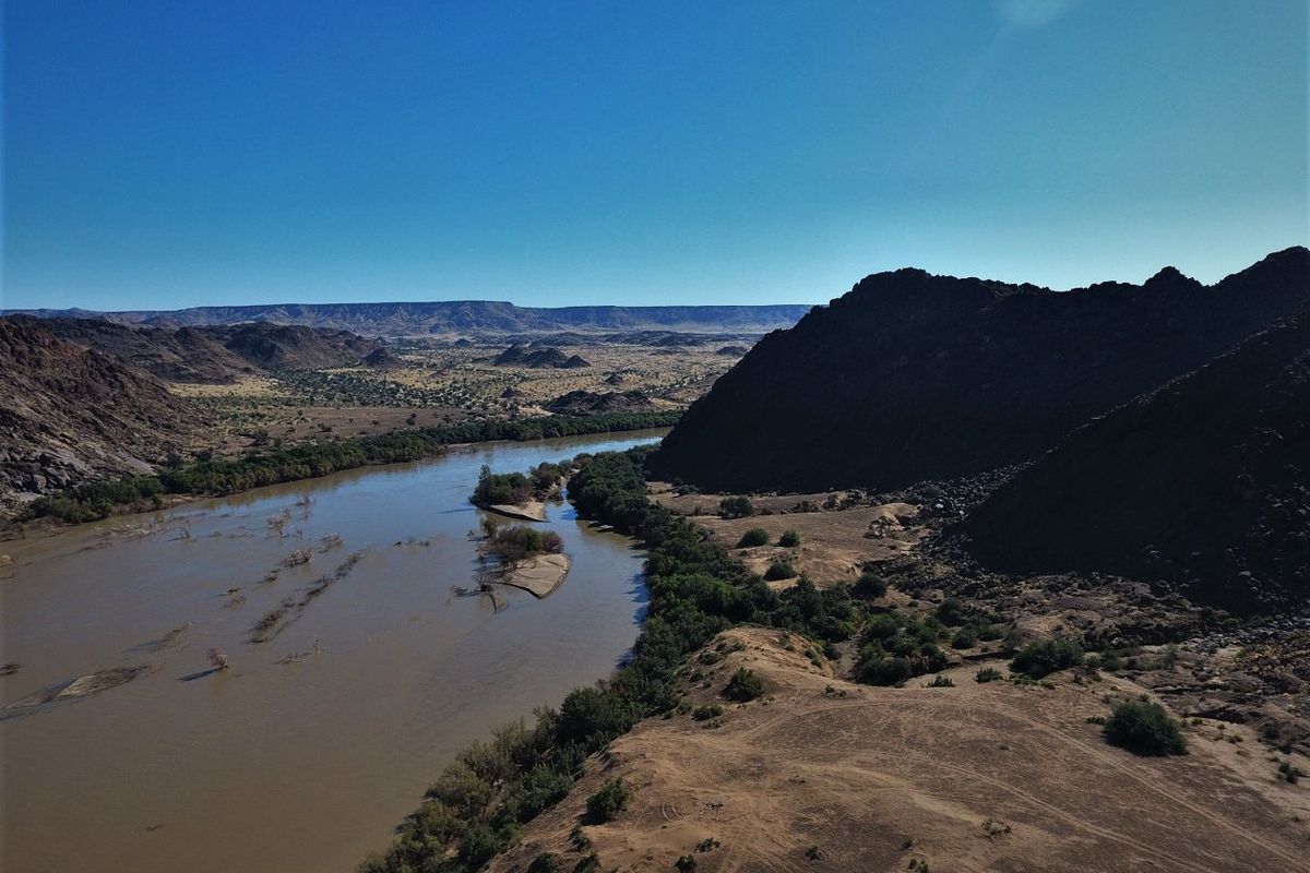 An aerial view of the expansive farm landscape featuring a winding river, rugged hills, and natural terrain.