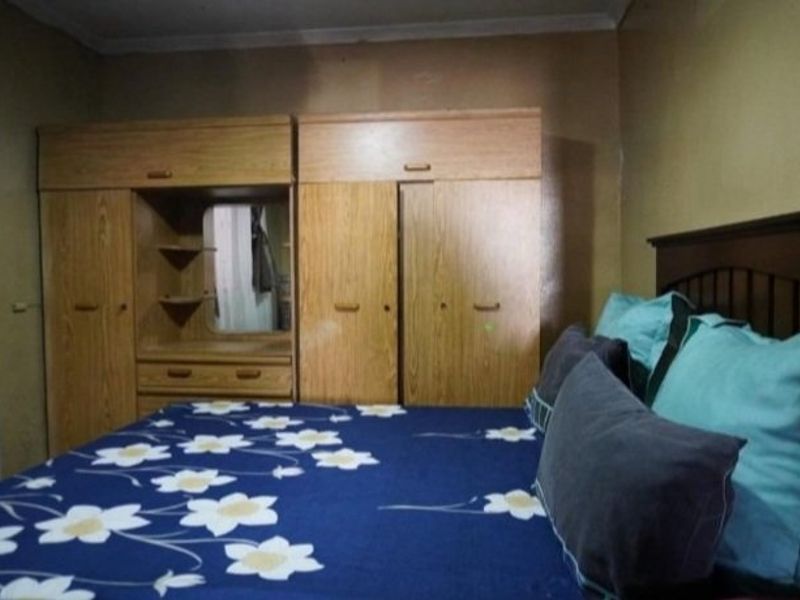 A bedroom featuring a large built-in wooden wardrobe unit with integrated shelving and storage.