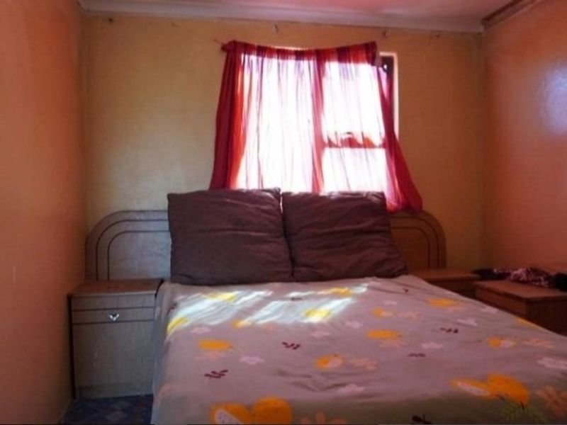 A bedroom featuring a built-in headboard and integrated bedside tables, requiring cosmetic updates to the wall finishes.