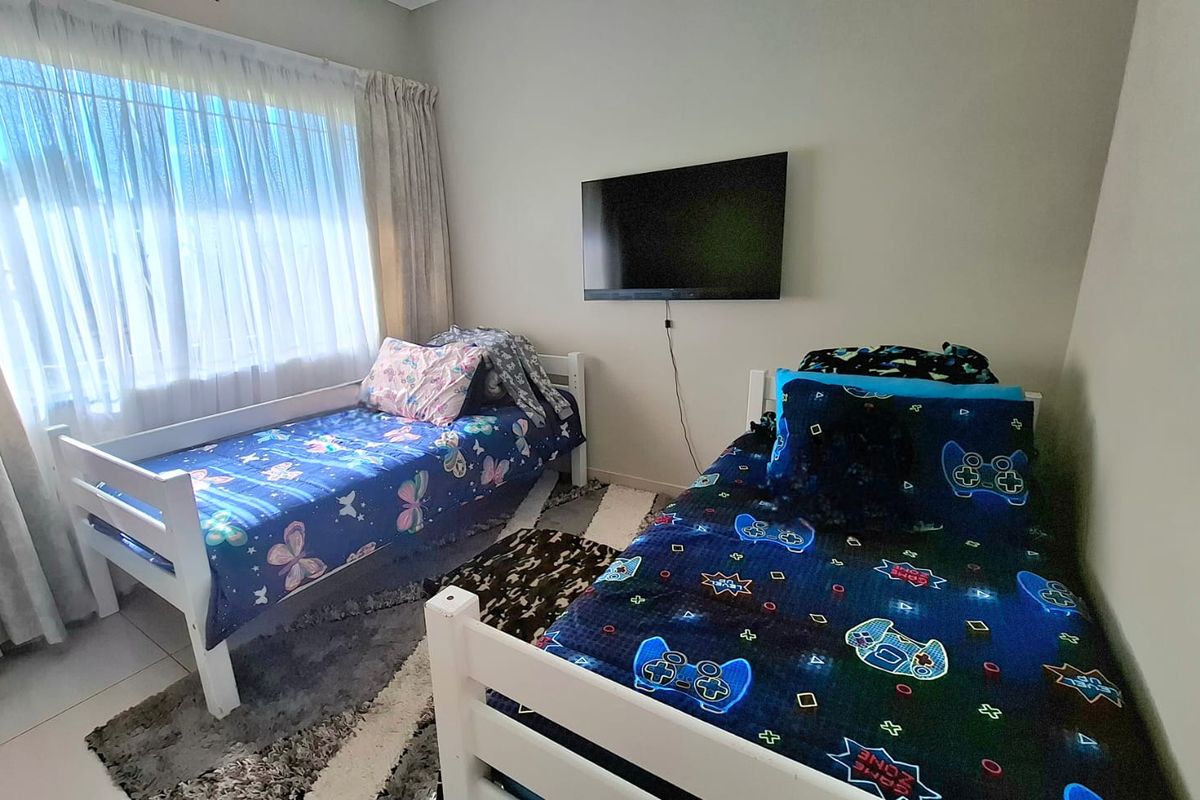 A functional bedroom featuring neutral wall tones, tiled flooring, and a wall-mounted television, providing a comfortable space for rest or recreation.