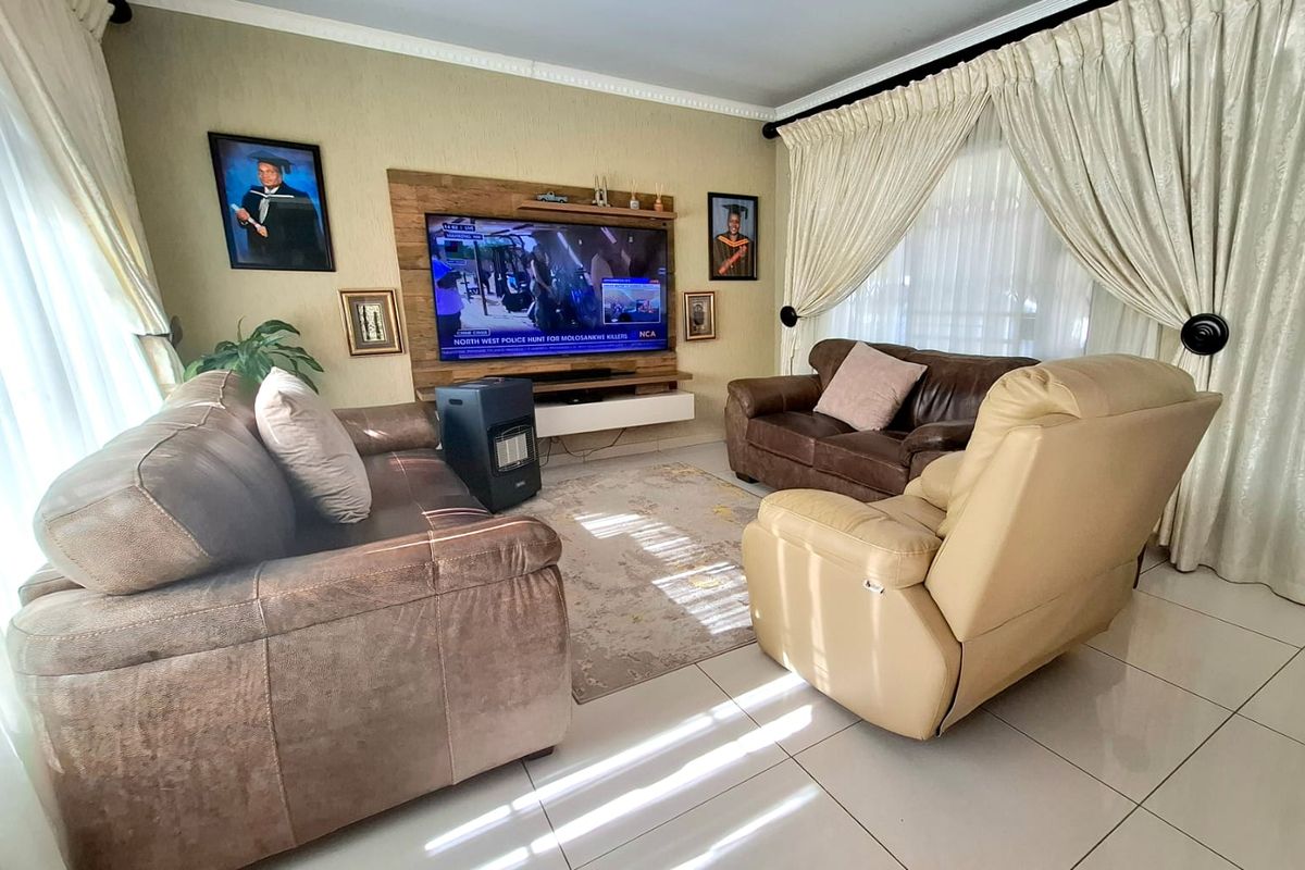 A comfortable living room featuring a built-in media unit, tiled flooring, and coved ceiling details, providing a functional and well-maintained space.