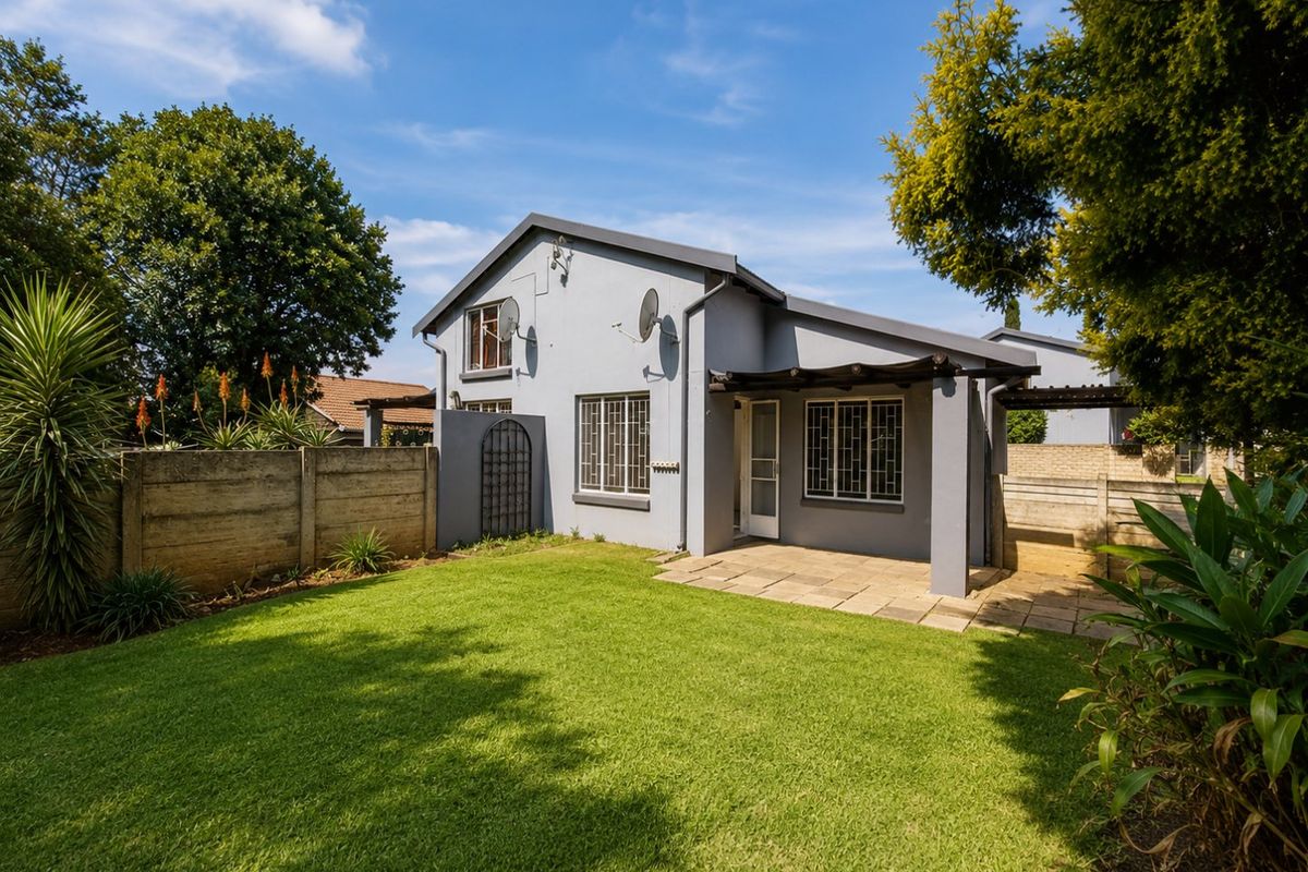 Rear view of the townhouse featuring a paved patio area, timber pergola, and a well-maintained private garden with perimeter walling.