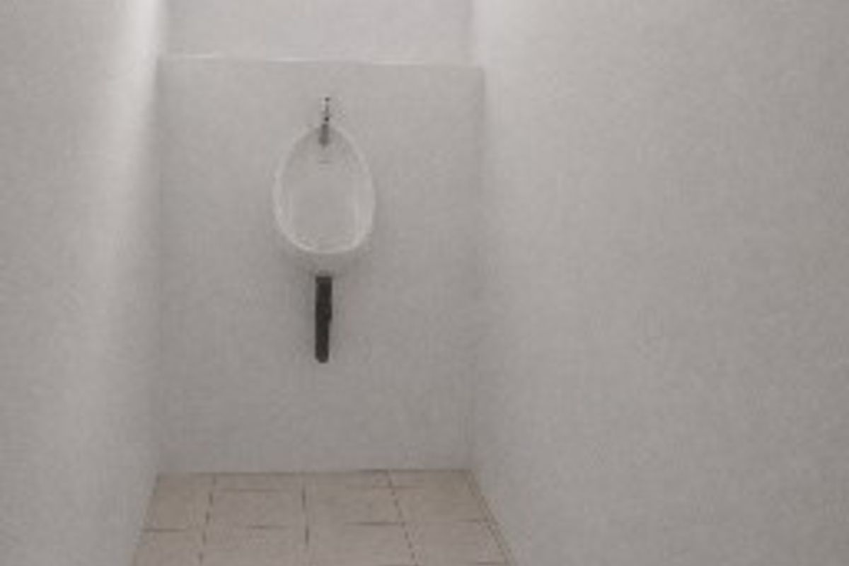 A functional commercial restroom facility featuring a wall-mounted urinal, tiled flooring, and a small window for natural light.