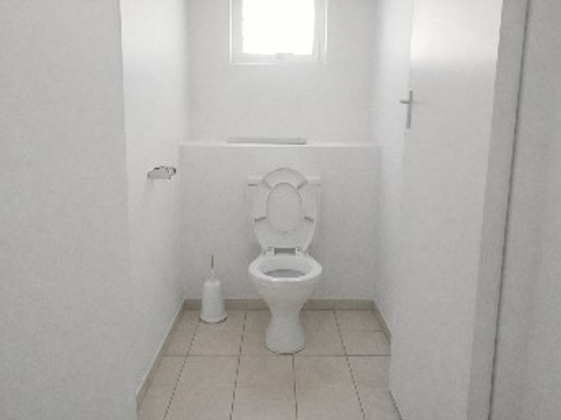 A compact, functional bathroom featuring tiled flooring and a standard toilet, providing essential facilities in a clean, minimalist space.