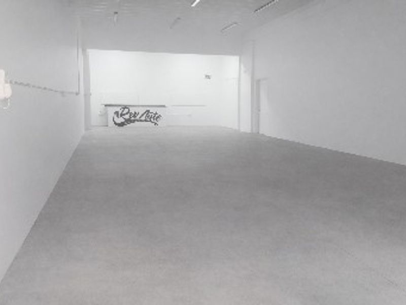 A spacious, empty industrial utility area featuring concrete flooring and overhead fluorescent lighting, suitable for various commercial or storage applications.