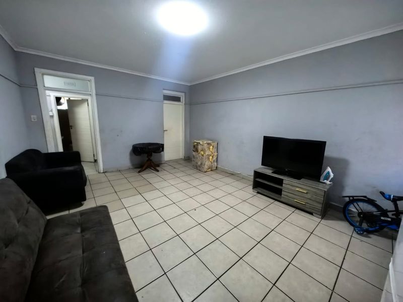 A spacious living room featuring neutral grey walls and tiled flooring, providing a functional base for personalization and interior design updates.
