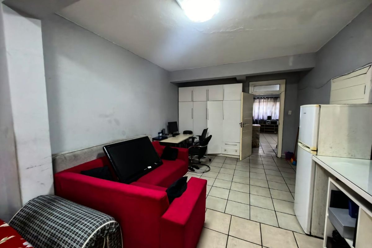 Open plan living area featuring tiled flooring and built-in cabinetry, providing a functional layout with direct access to an adjoining room.