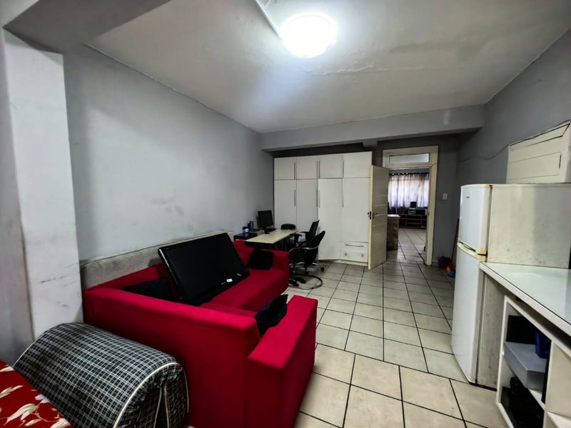 Open plan living area featuring tiled flooring and built-in cabinetry, providing a functional layout with direct access to an adjoining room.