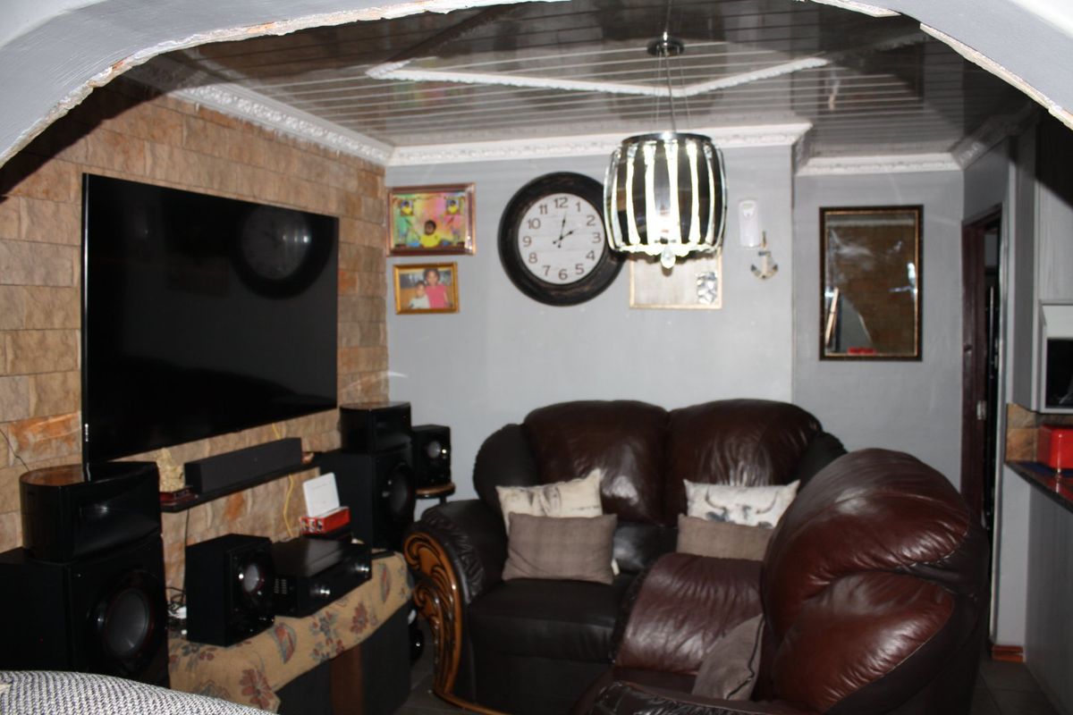 A living room featuring a stone-clad feature wall, a suspended ceiling with decorative molding, and an arched entryway.