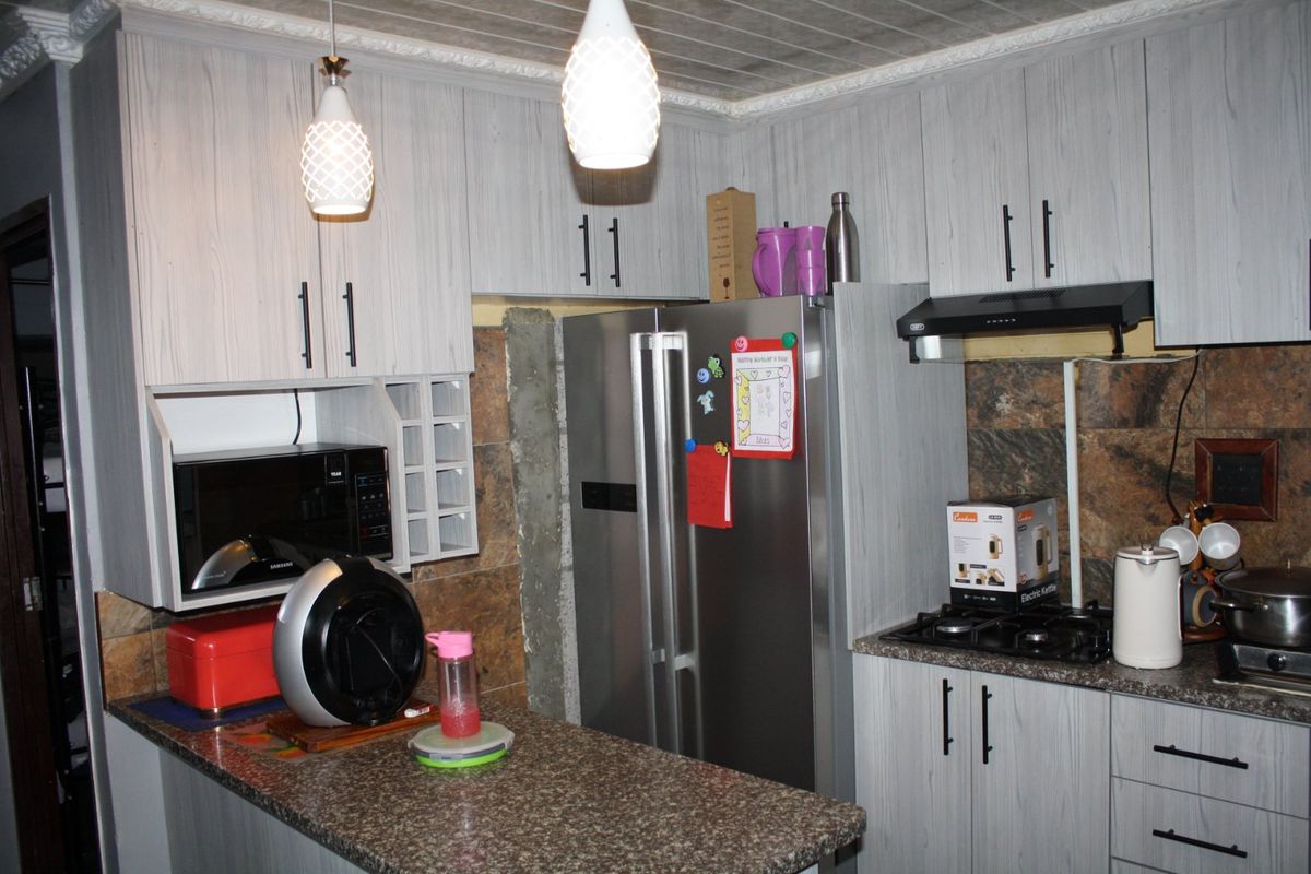 A functional kitchen featuring light wood-grain cabinetry, granite countertops, a built-in gas hob, and an extractor fan.