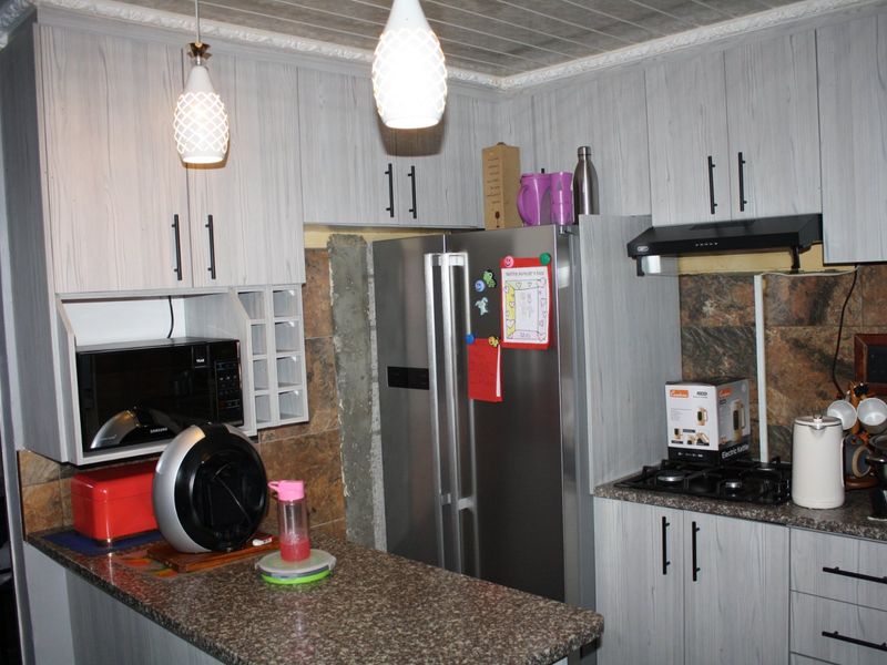 A functional kitchen featuring light wood-grain cabinetry, granite countertops, a built-in gas hob, and an extractor fan.