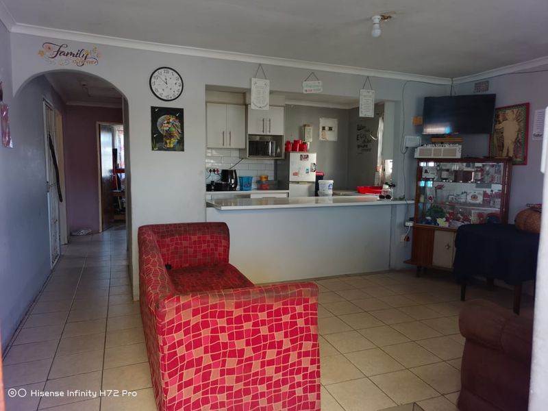 Open-plan living area featuring a breakfast bar, tiled flooring, and an adjoining kitchen with built-in cabinetry.