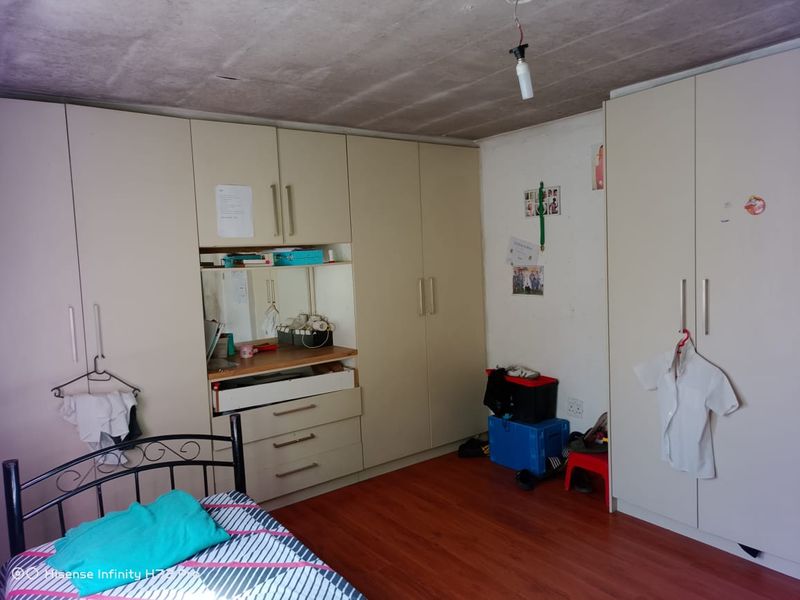 Bedroom featuring extensive built-in cupboard storage, laminate flooring, and an unfinished concrete ceiling.