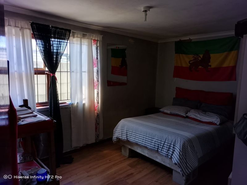 A bedroom featuring laminate flooring and a window, providing natural light to the space.