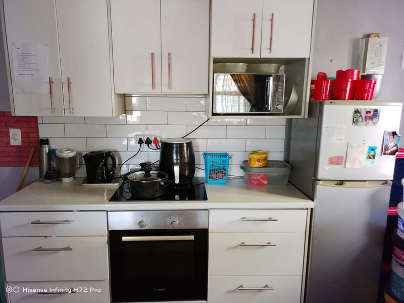 A functional kitchen featuring white cabinetry, a subway tile backsplash, a built-in oven, and an electric hob.