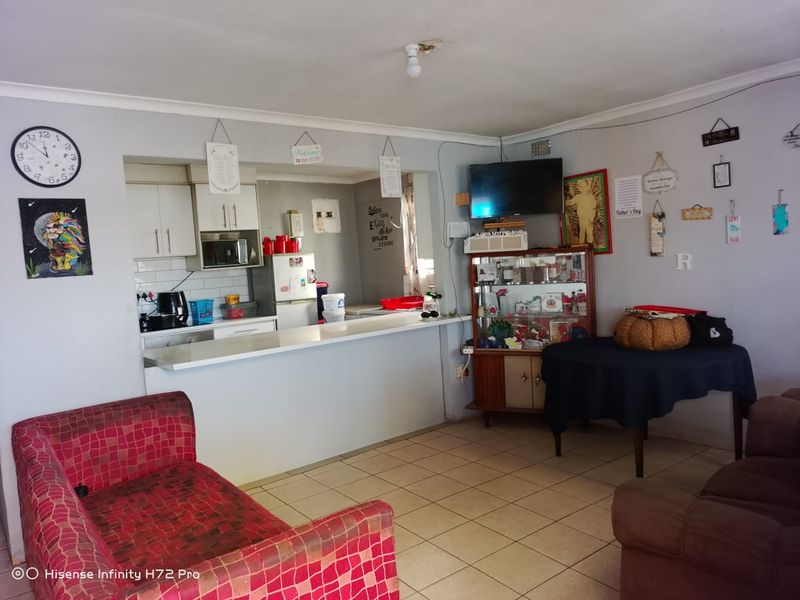 Open plan living area featuring a kitchen with breakfast bar and tiled flooring, requiring cosmetic updates to improve the overall aesthetic.
