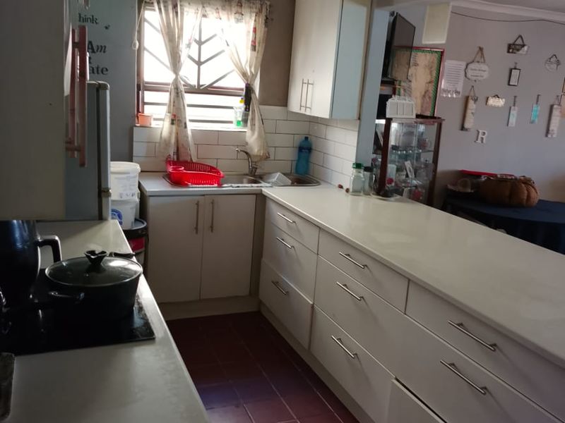 Functional kitchen featuring white built-in cabinetry, laminate countertops, subway tile backsplash, and ceramic tile flooring with a window providing natural light.
