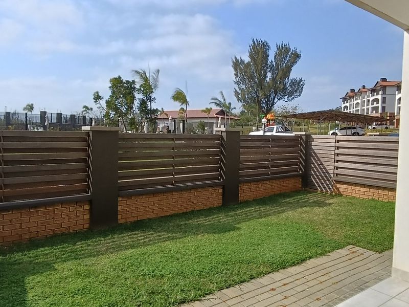 A private covered patio area featuring paved flooring and a secure brick and slatted timber boundary wall overlooking the garden.