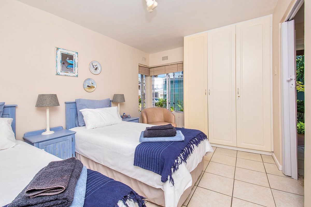 A bedroom featuring tiled flooring and built-in cupboards, offering a functional space with natural light from the window.