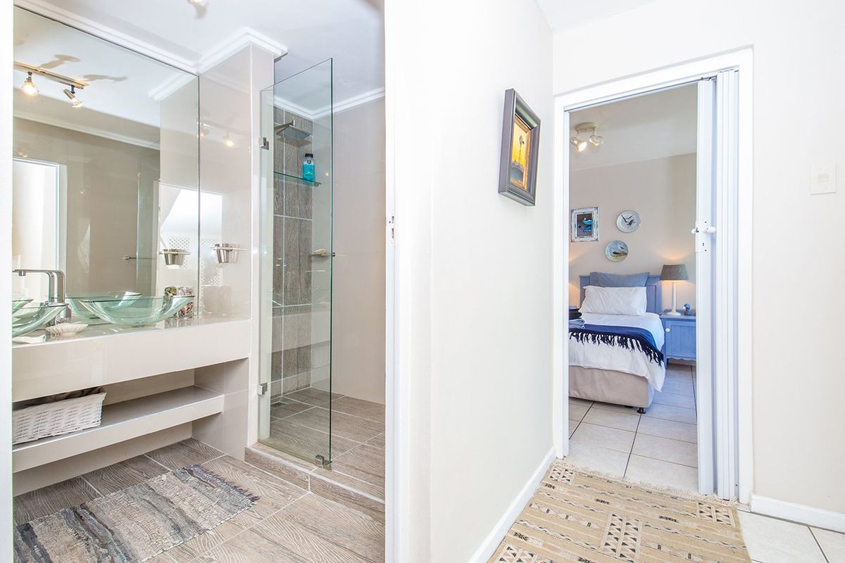 Modern bathroom featuring a glass vessel sink, wall-mounted faucet, and a frameless glass shower enclosure with a rain shower head.