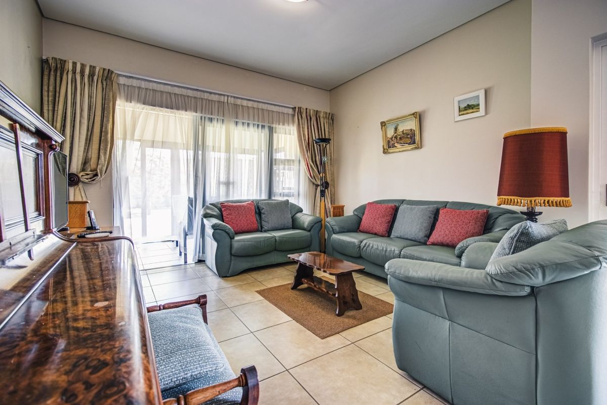 A spacious living room featuring neutral tiled flooring and large sliding glass doors that provide direct access to the outdoor patio area.
