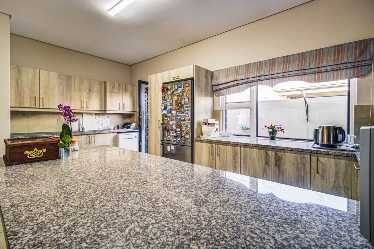 A functional kitchen featuring granite countertops, ample laminate cabinetry, and a central island, providing a practical workspace for cooking and meal preparation.