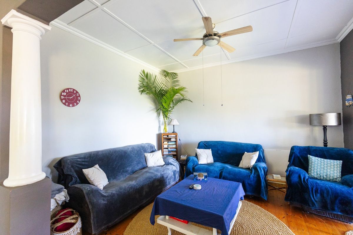 A living room featuring timber flooring, a ceiling fan, and a decorative column, providing a comfortable and functional space.