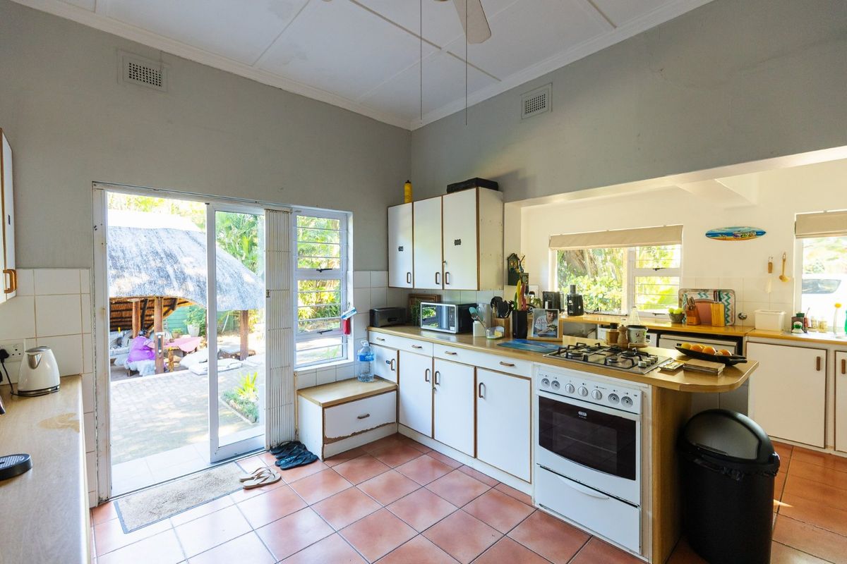 Functional kitchen featuring white cabinetry, built-in oven and gas hob, tiled flooring, and direct access to the outdoor patio area.