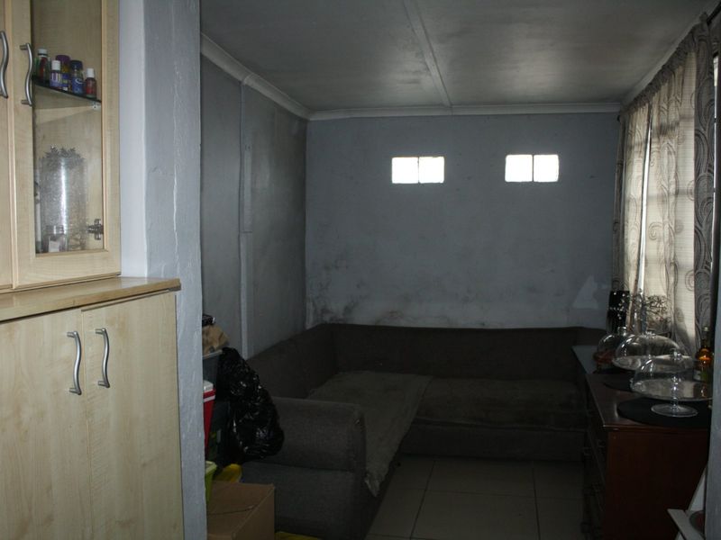 A living room space featuring built-in cabinetry and tiled flooring, currently showing signs of significant wall dampness and deterioration requiring maintenance.