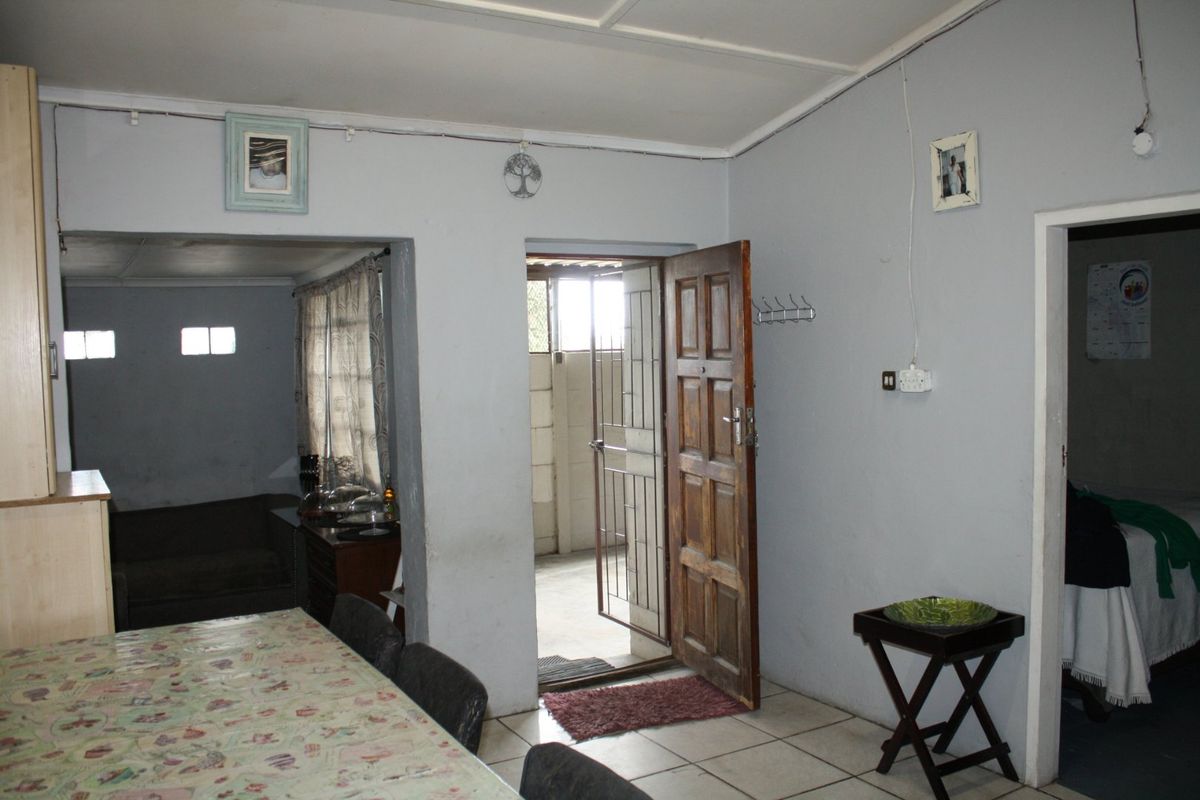 A living area featuring tiled flooring and direct access to an exterior space through a timber door with a security gate.