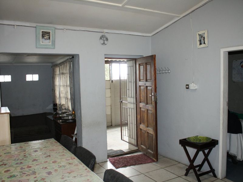 A living area featuring tiled flooring and direct access to an exterior space through a timber door with a security gate.