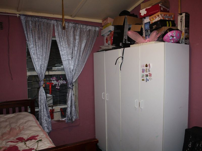 A bedroom featuring a built-in wardrobe and louvered window, requiring cosmetic updates to improve the overall condition and aesthetic appeal.